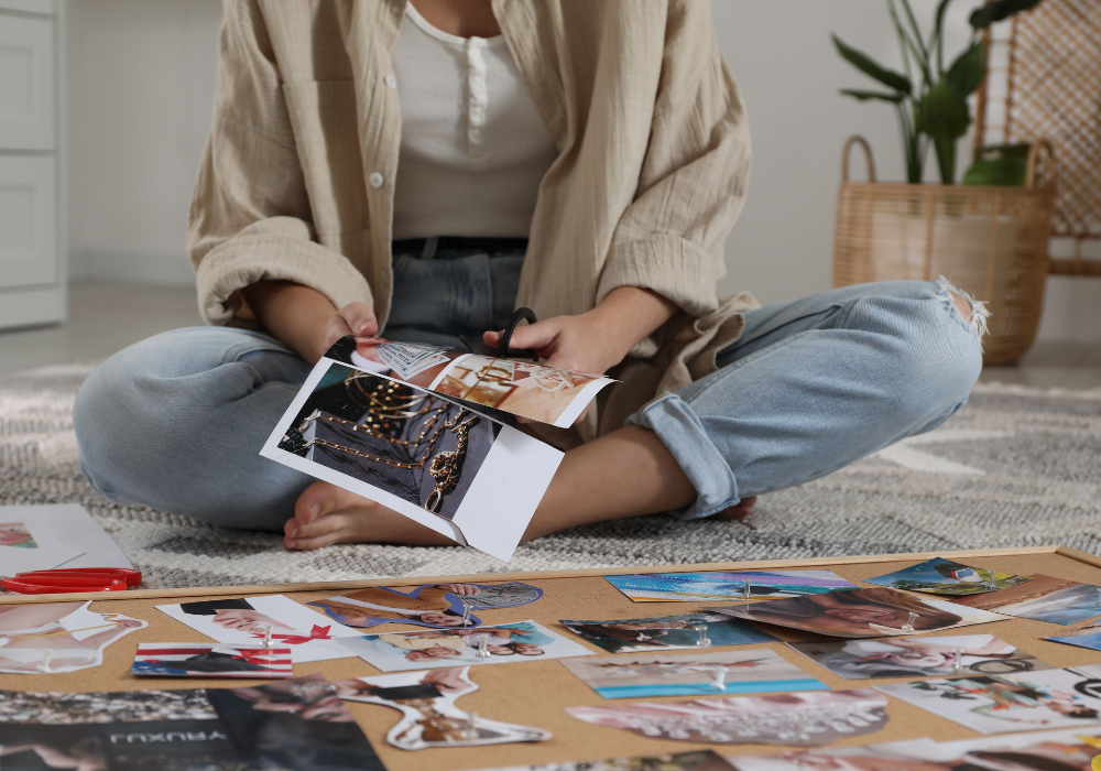 woman sitting on floor cutting out items for vision board.