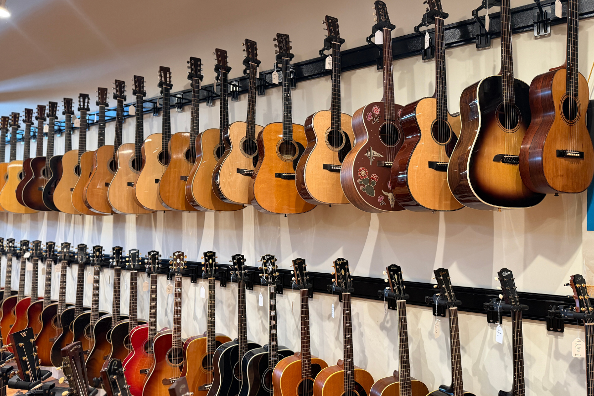 Acoustic guitars hanging on a wall inside a guitar shop.