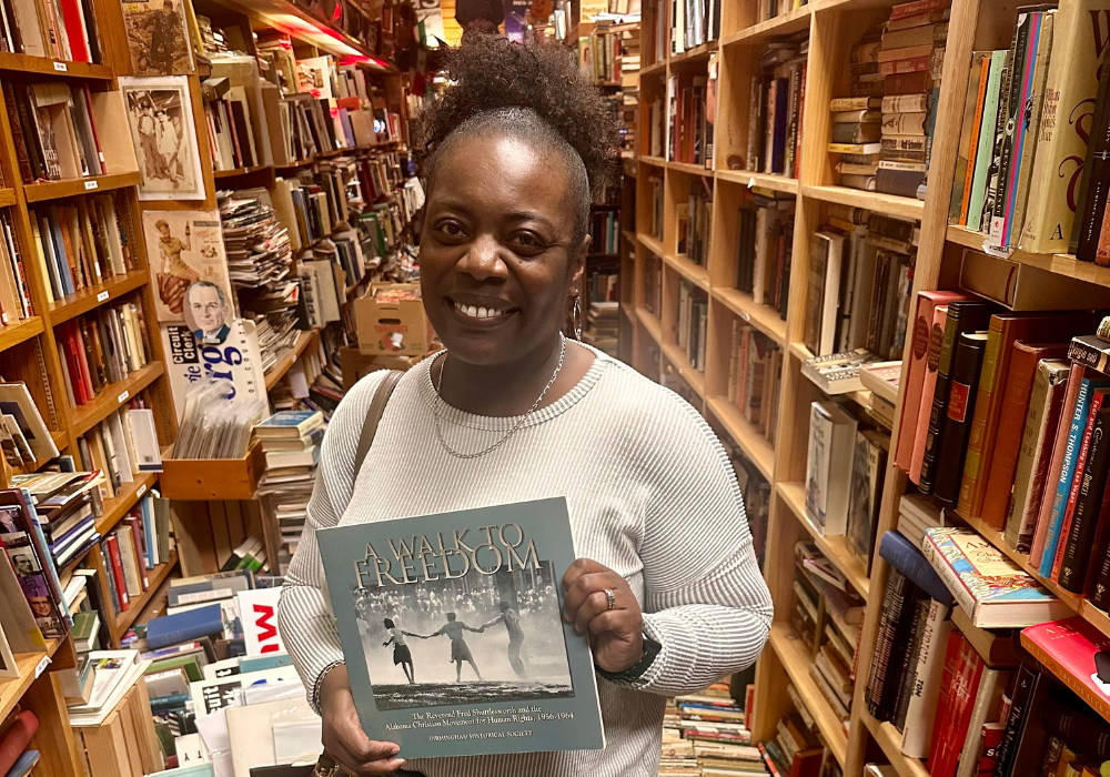 Jim Reed Books 1 » WhatCherithInks woman standing in bookstore holding book and smiling.
