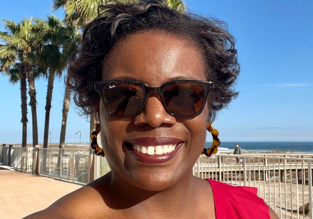 woman taking a selfie with the beach in the background.